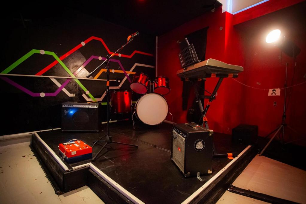 A grungy stage with a drum set, keyboard, and amps