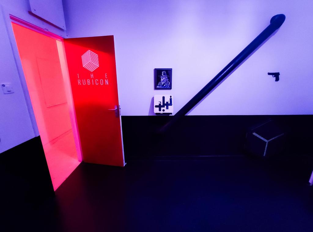 A minimalist black and white room with a red door that says "The Rubicon"