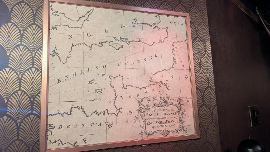 A map of the English Channel on a wall, with a lighted path between Paris and London
