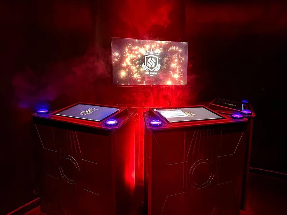 Pedestals with a screen and glowing buttons, with the Lock Academy logo in the background