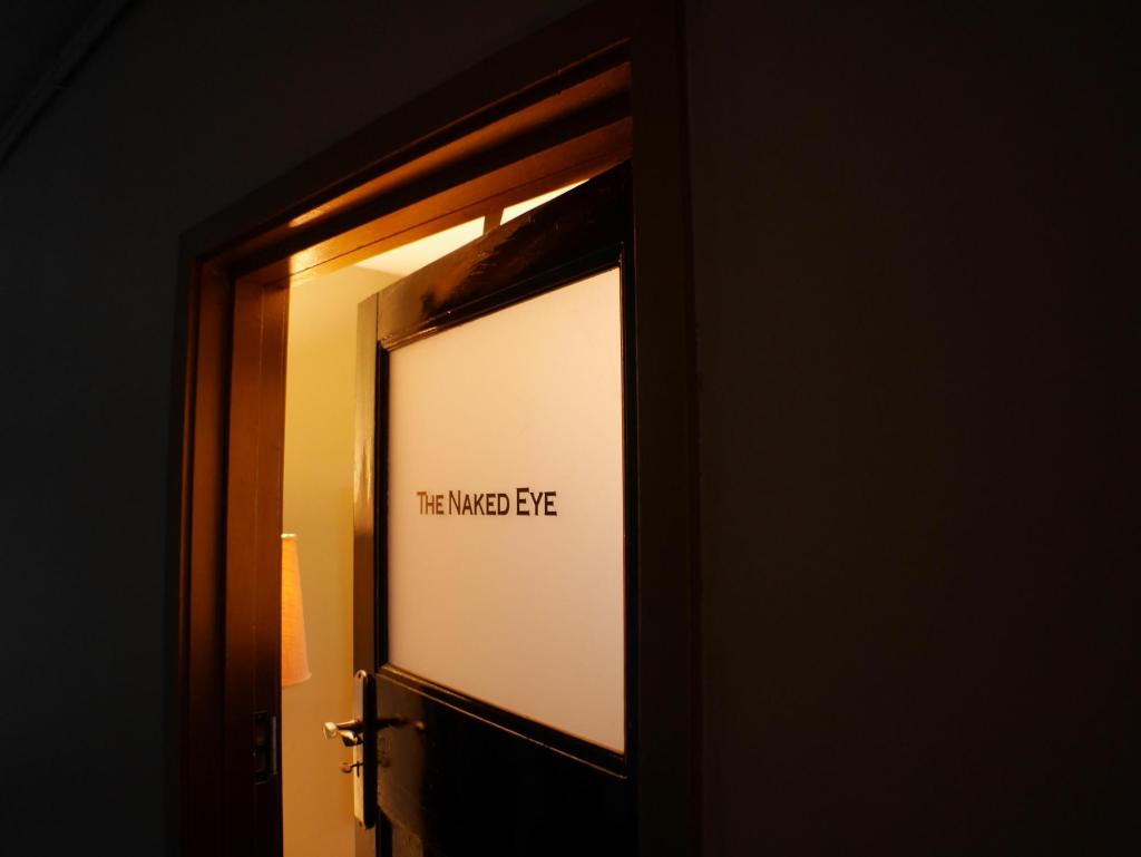 A slightly ajar door labeled "The Naked Eye"