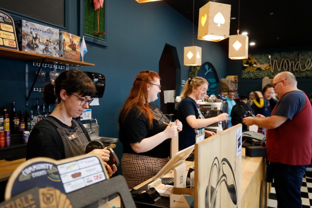 baristas lined up at a busy cafe with wonderland decorations