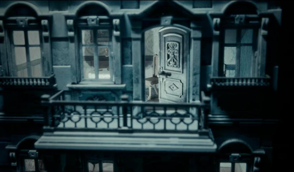 Closeup image of a small balcony with an open door leading into a house, all in shades of gray.