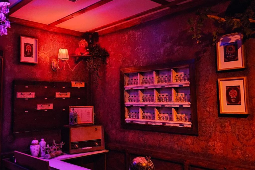 A dreamily lit lobby with an old radio, a rack of clipboards, and an array of glass bottles