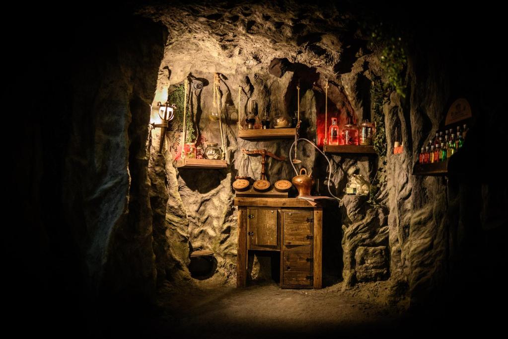 A magical apothecary in a cave, with an assortment of colorful glowing bottles