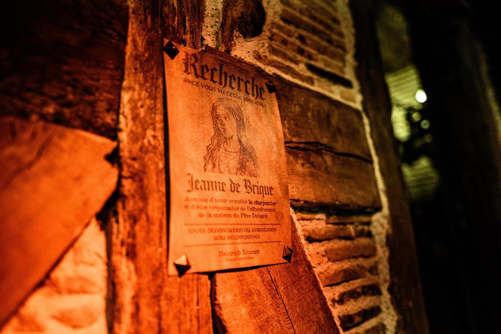 A wanted poster for a medieval witch, pinned onto a wooden and stone wall
