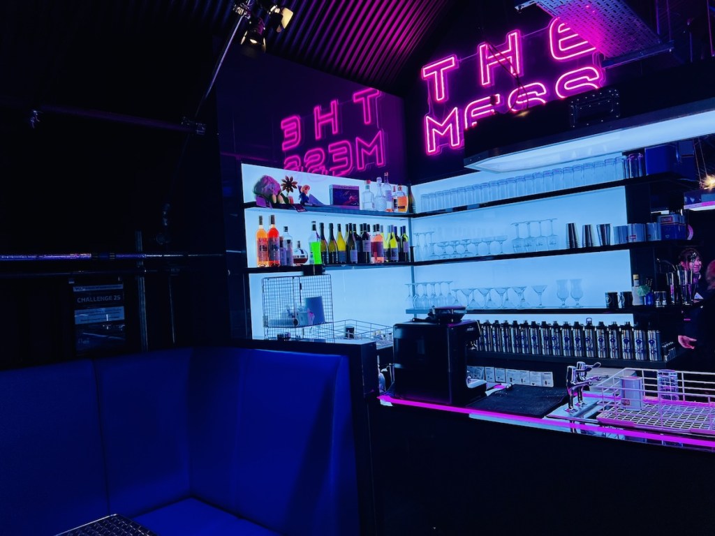 Neon-lit bar named, "The Mess"
