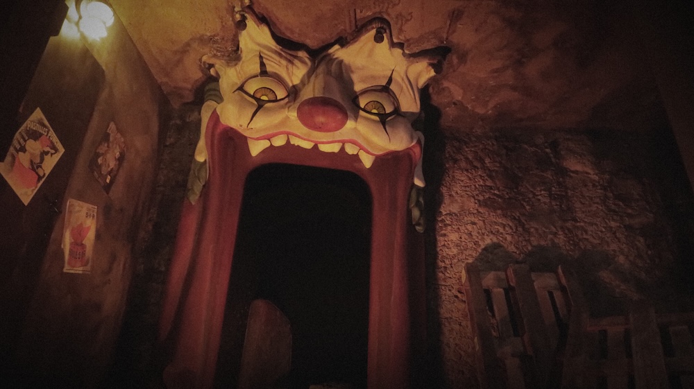 an entrance through a large, red, open clown's mouth, with teeth right above the door, a red nose, and eyes looking down