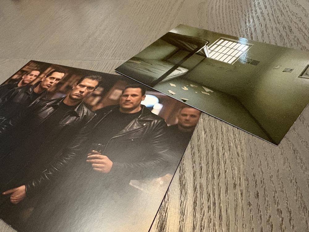 Two photos spread out on a table: one of 5 men in black leather jackets and the other of a prison cell with a bunk bed and a window. Note the 6 fingers.