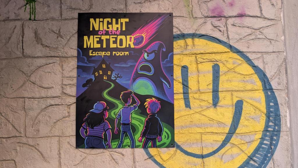A poster for Night of the Meteor Escape Room posted on a brick wall with smiley face graffiti behind