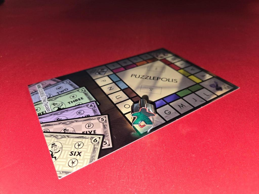 Postcard on red table with a metal Meeple game piece placed on the start space.