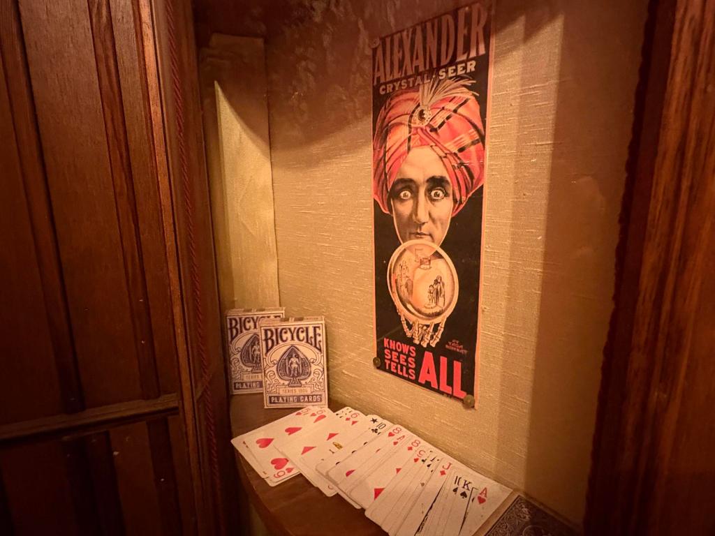Image of a cabinet showing a poster of a fortune teller, two decks of cards, and playing cards spread out.