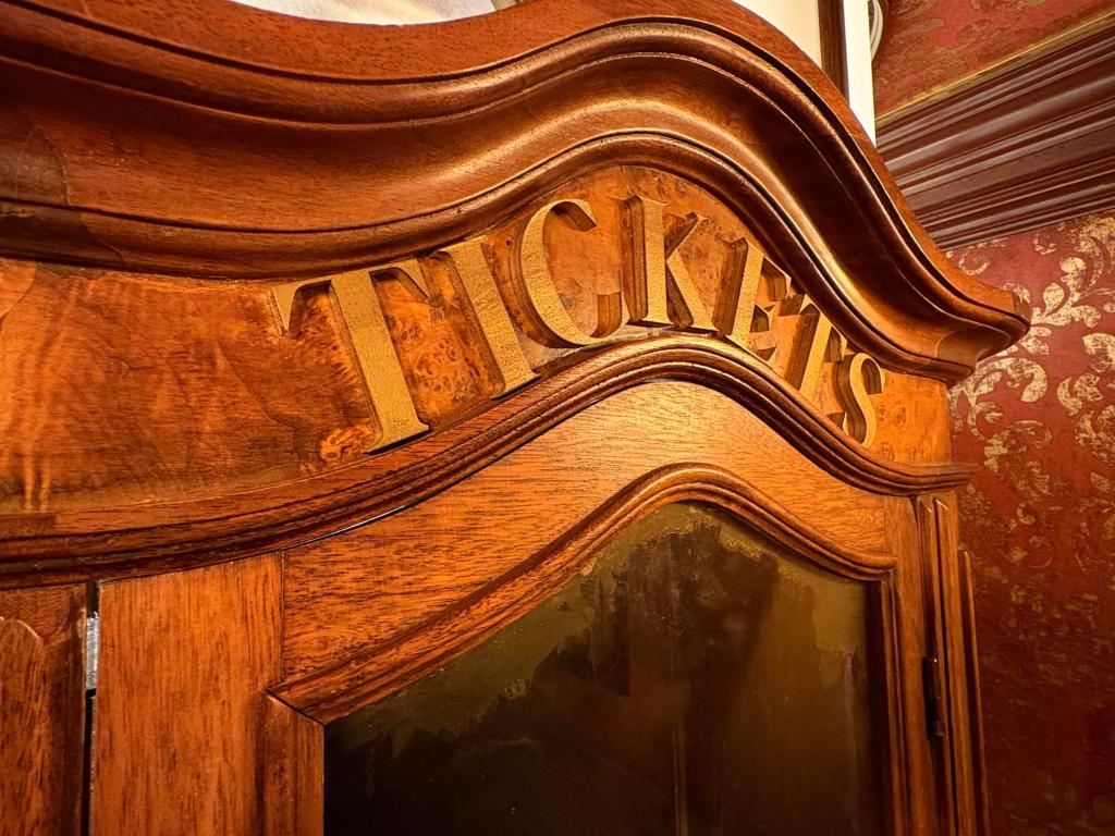 Closeup of the curved top of a wooden ticket booth showing the word Tickets.