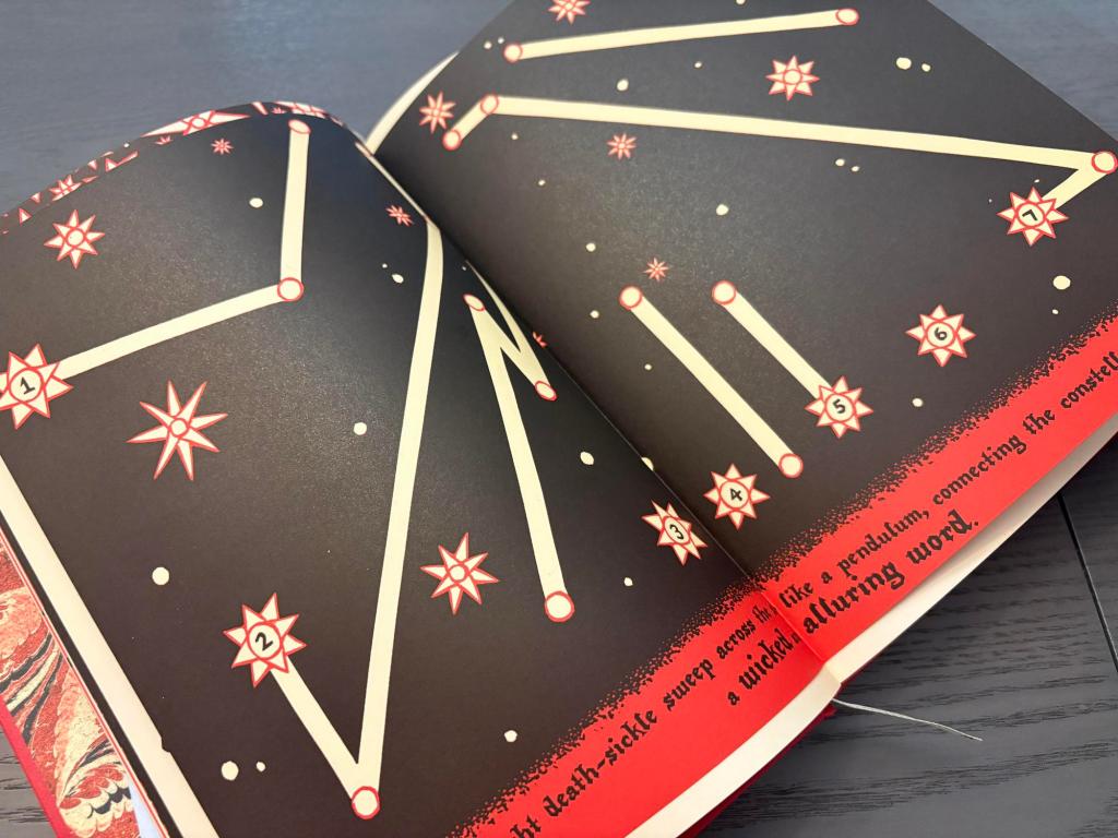 An opened book on a grey table. The two-page linocut illustration depicts white stars with red borders on a black background. The footer of the pages has medieval-looking text describing how a character swept their sickle across the sky. The stars in the illustration occasionally have thick white lines connecting them to form rudimentary constellations.