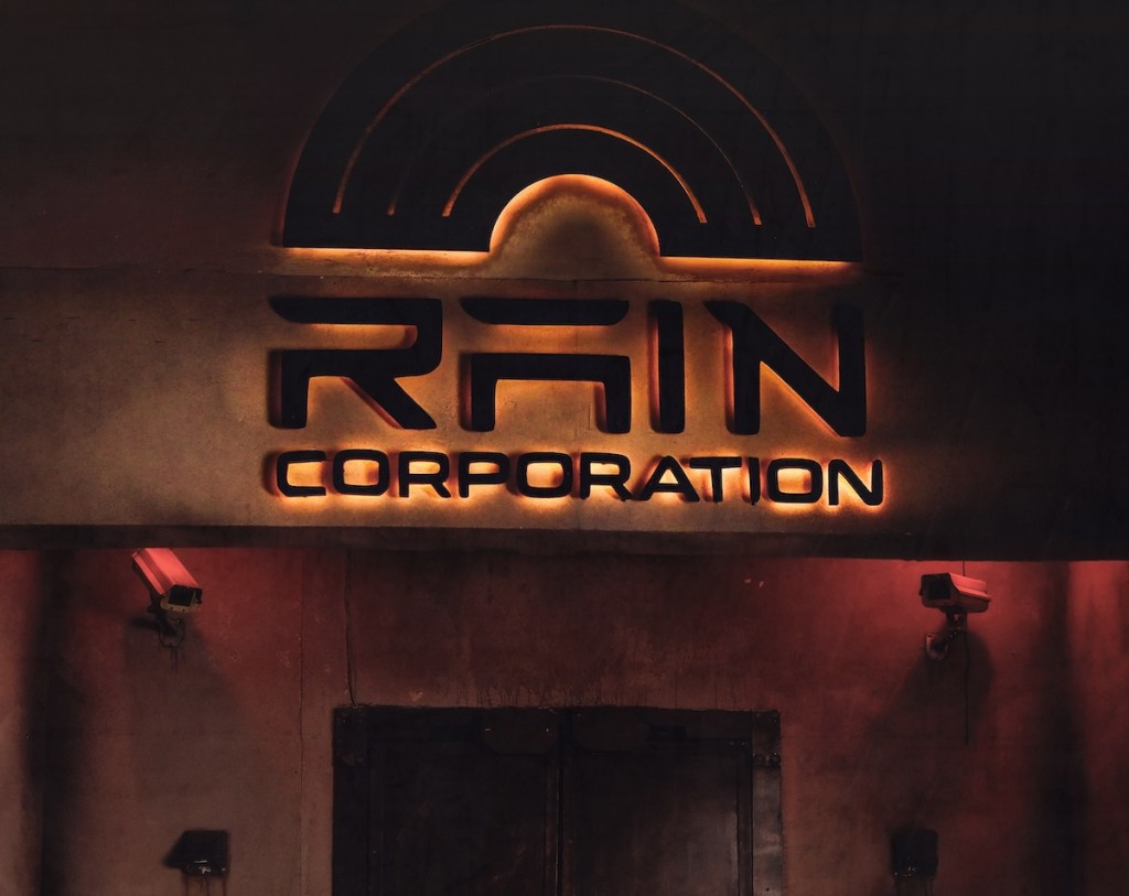A building with Rain Corporation's branding. The building has two security cameras below the logo.