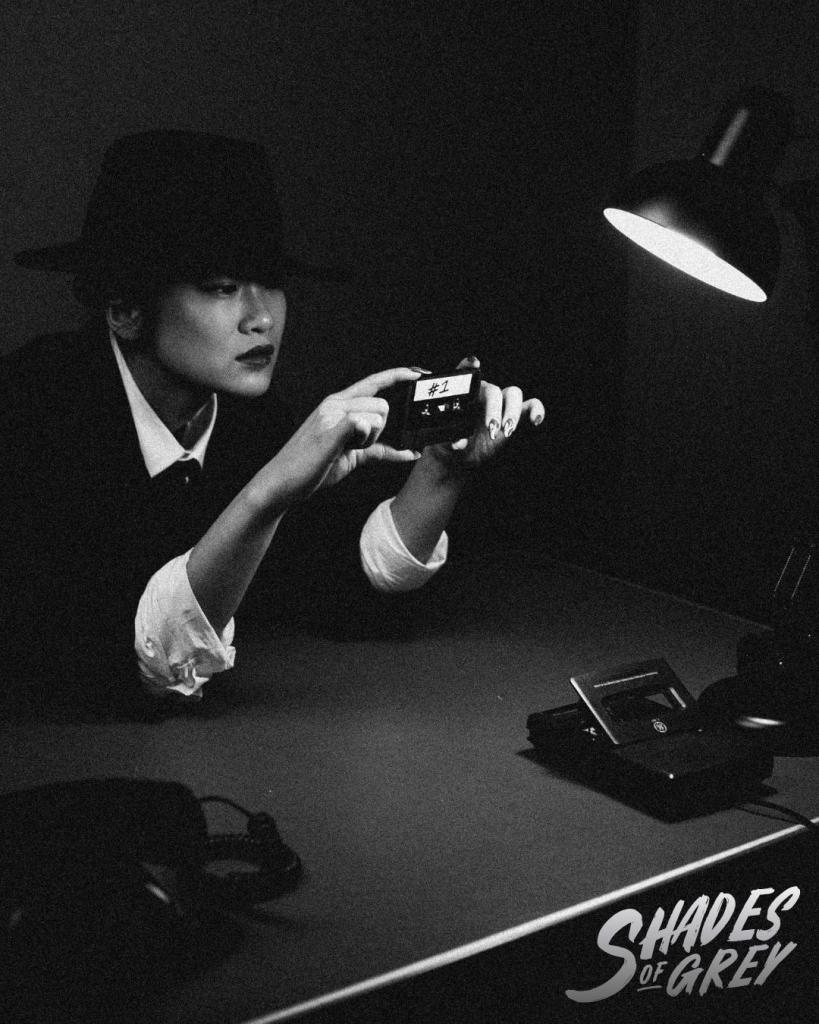 A detective at a desk holding a cassette tape