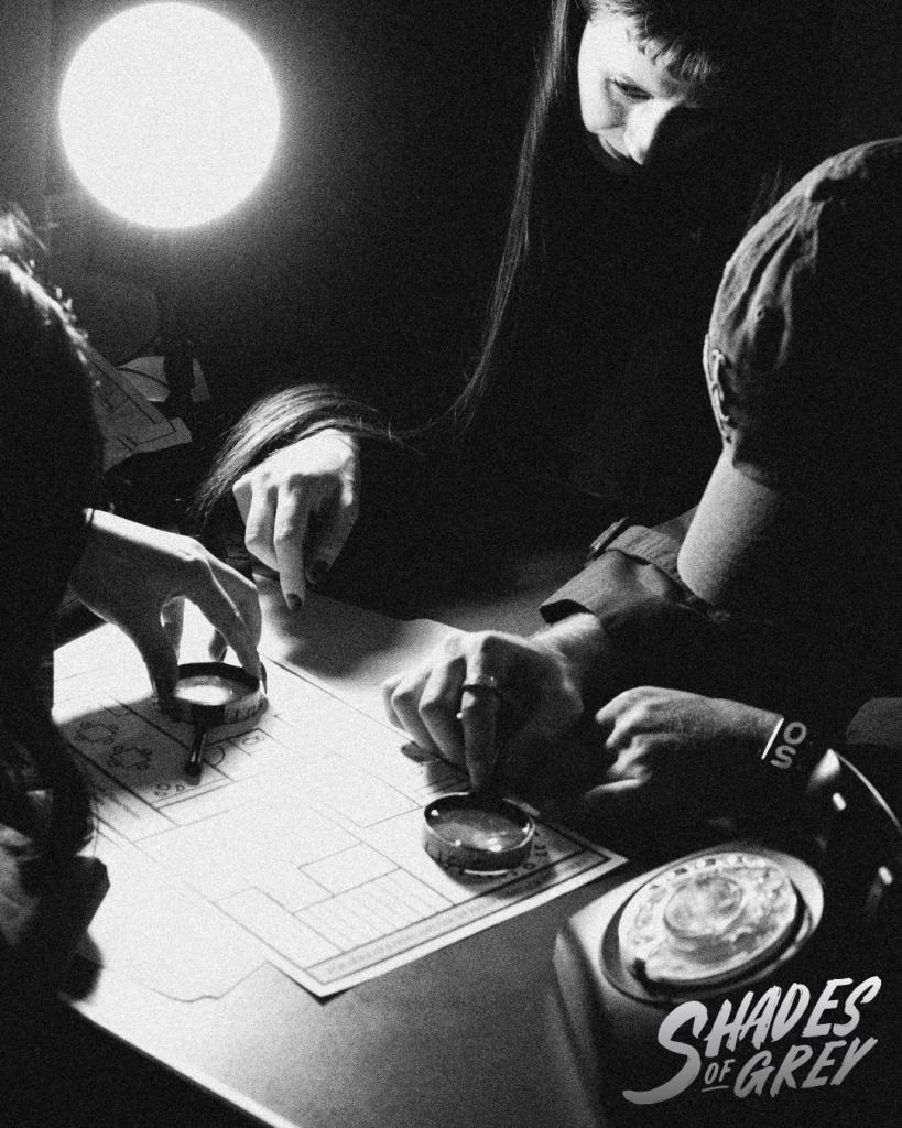 Players holding magnifying glasses up to a map on a desk