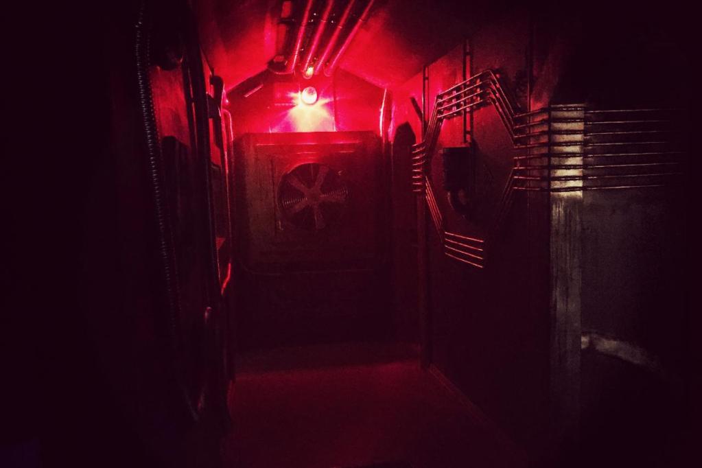 The end of a dark hallway with pipes running along the walls
