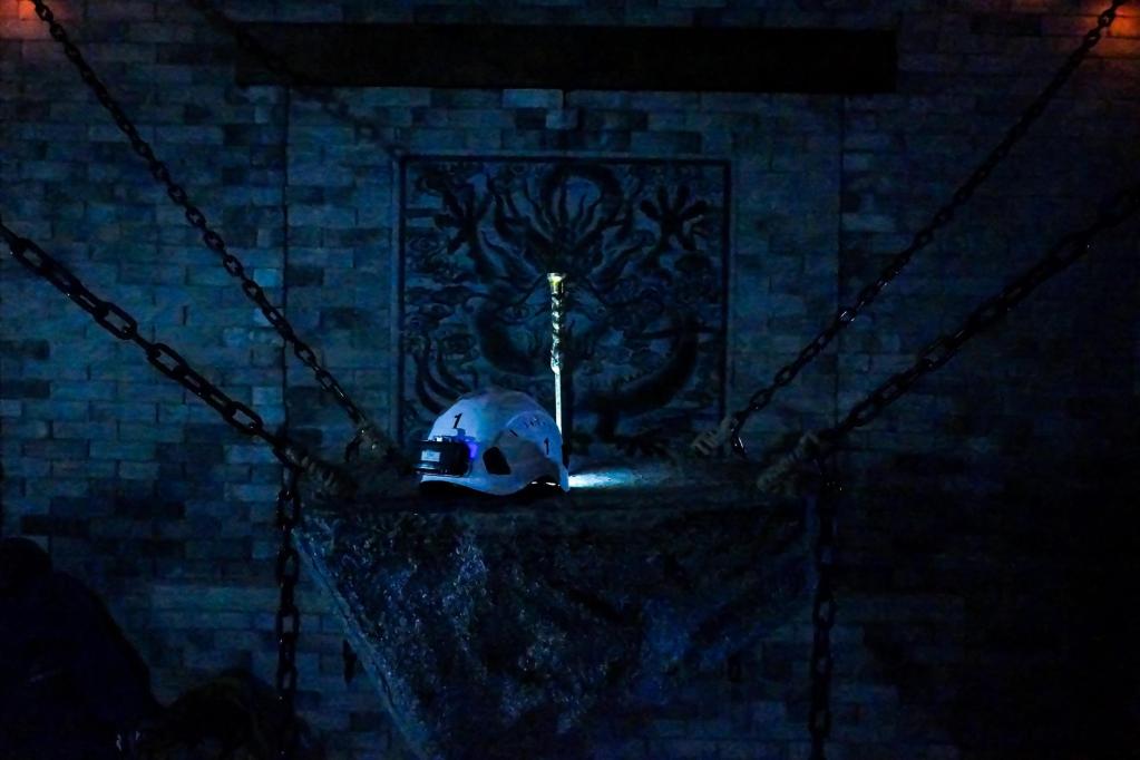 A sword embedded in a large block of stone suspended by metal chains