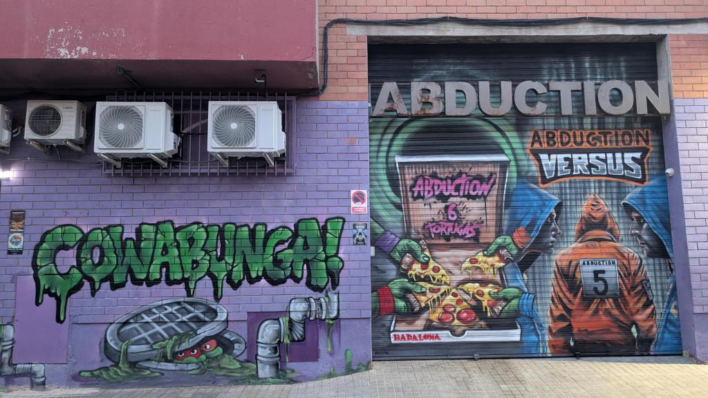 Abduction's facade with murals of some Ninja Turtles poking out from a manhole cover and turtle hands reaching into a box of pizza