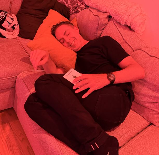 Man lying on couch with eyes closed and knees drawn to chest