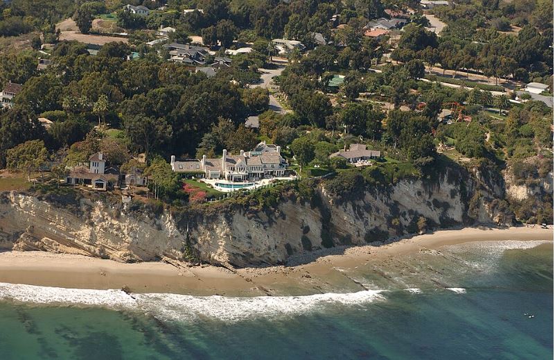 aerial photograph of california coastline, including a large mansion right on the cliff edge.