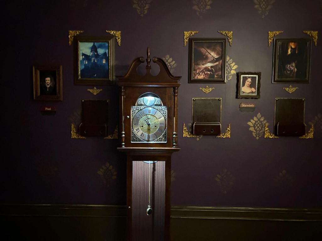 A grandfather clock surrounded by several small pictures and mounted wooden boxes.