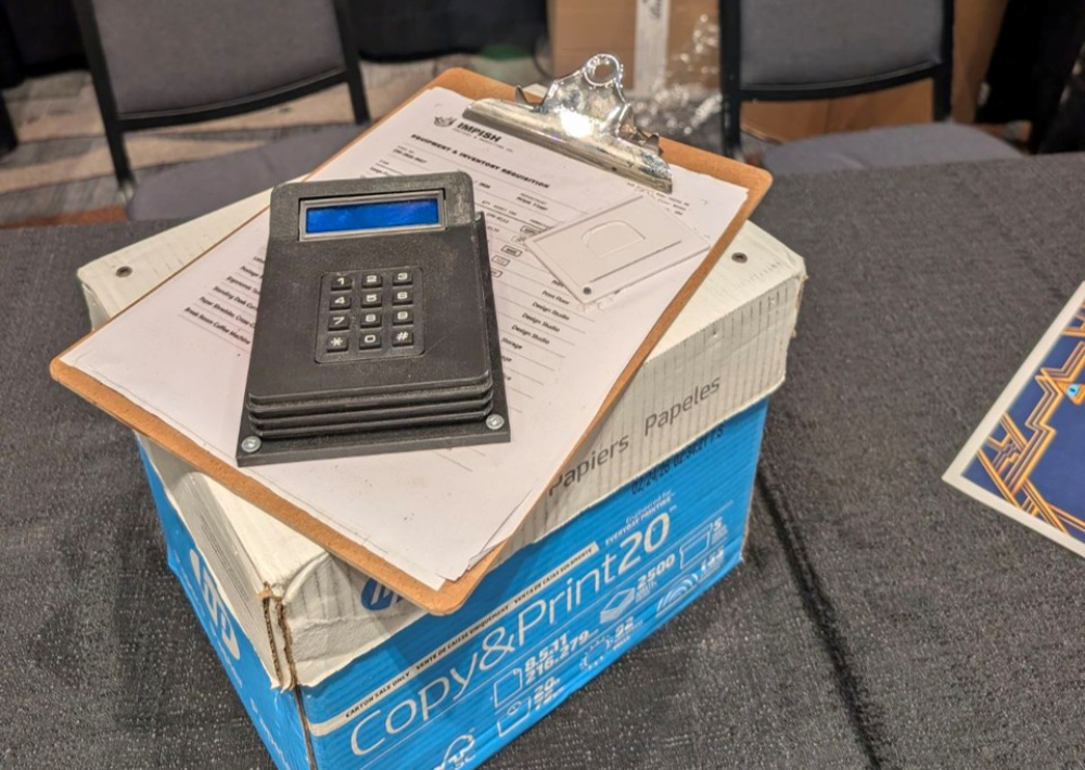 Image of a box, clipboard, and a receipt printer that were used as part of the RECON 26 game.