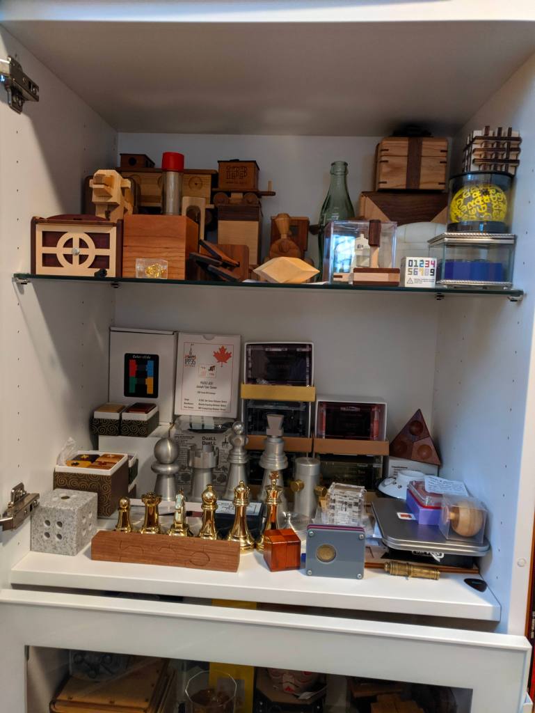 shelf of wooden puzzle boxes and chess piece puzzles