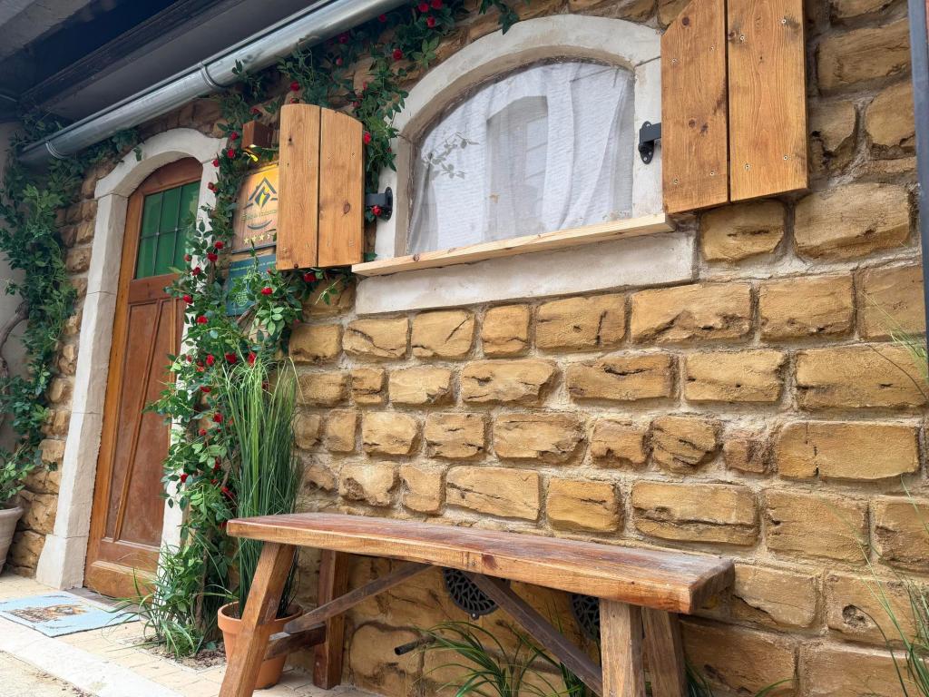 Image of front of a stone cottage, with arched doorways and windows, and a wooden bench under the window.