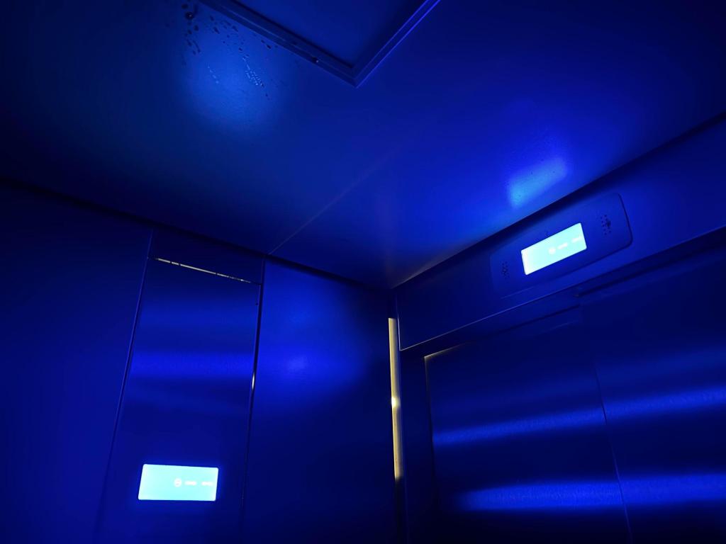 The inside of an elevator with the power out, bathed only in the blue light of the floor indicator.