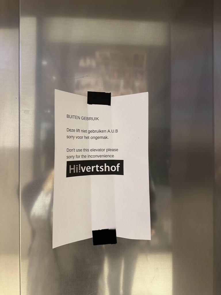 A paper notice in Dutch hung on an elevator apologizing for the elevator being out of service.