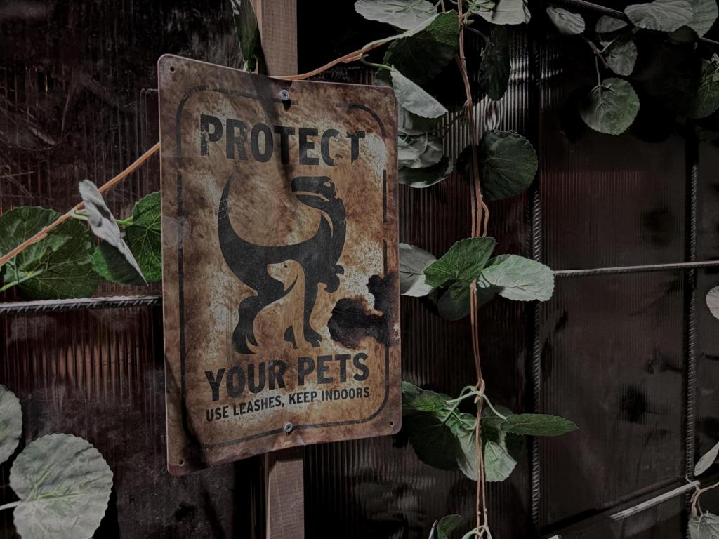 Closeup of a rusty sign with a dinosaur that says Protect your Pets, use leashes, keep indoors