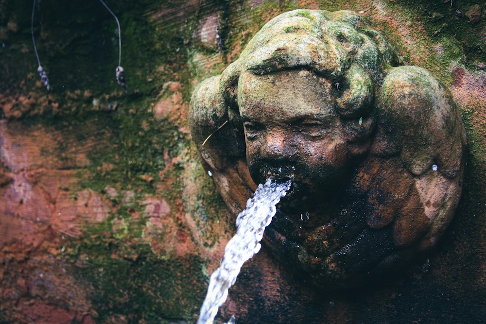 Sculptural baby angle water feature spraying water out of its mouth.