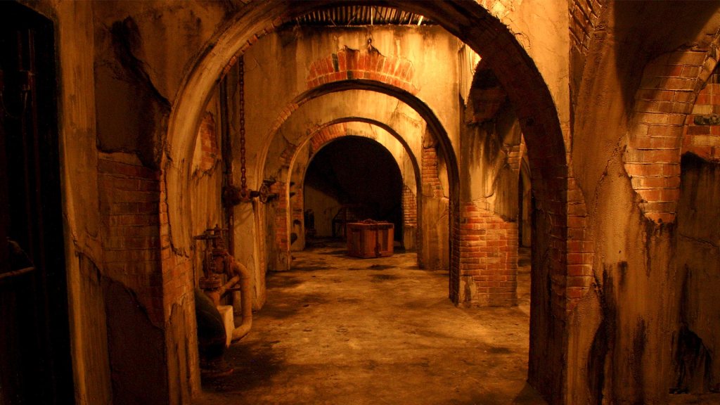 dimly lit hallway with many brick stone arches in basement
