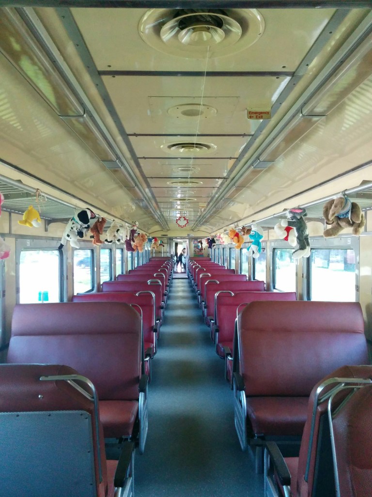 empty 60's era train with little stuffed animals dangling from the luggage compartment