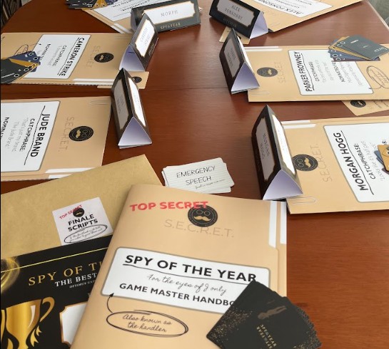 file folders arranged on a table that say "spy of the year" and have various names of secret agents.